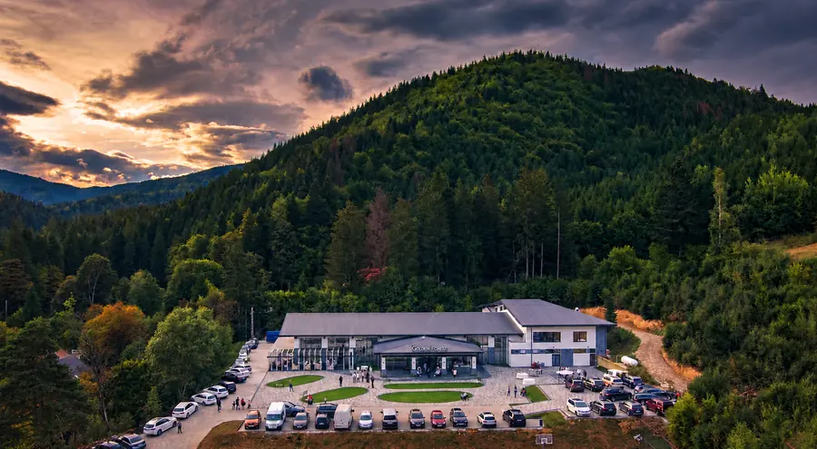 Parcarea Golden Forest văzută de sus, în fața clădirii, cu pădurea în jur